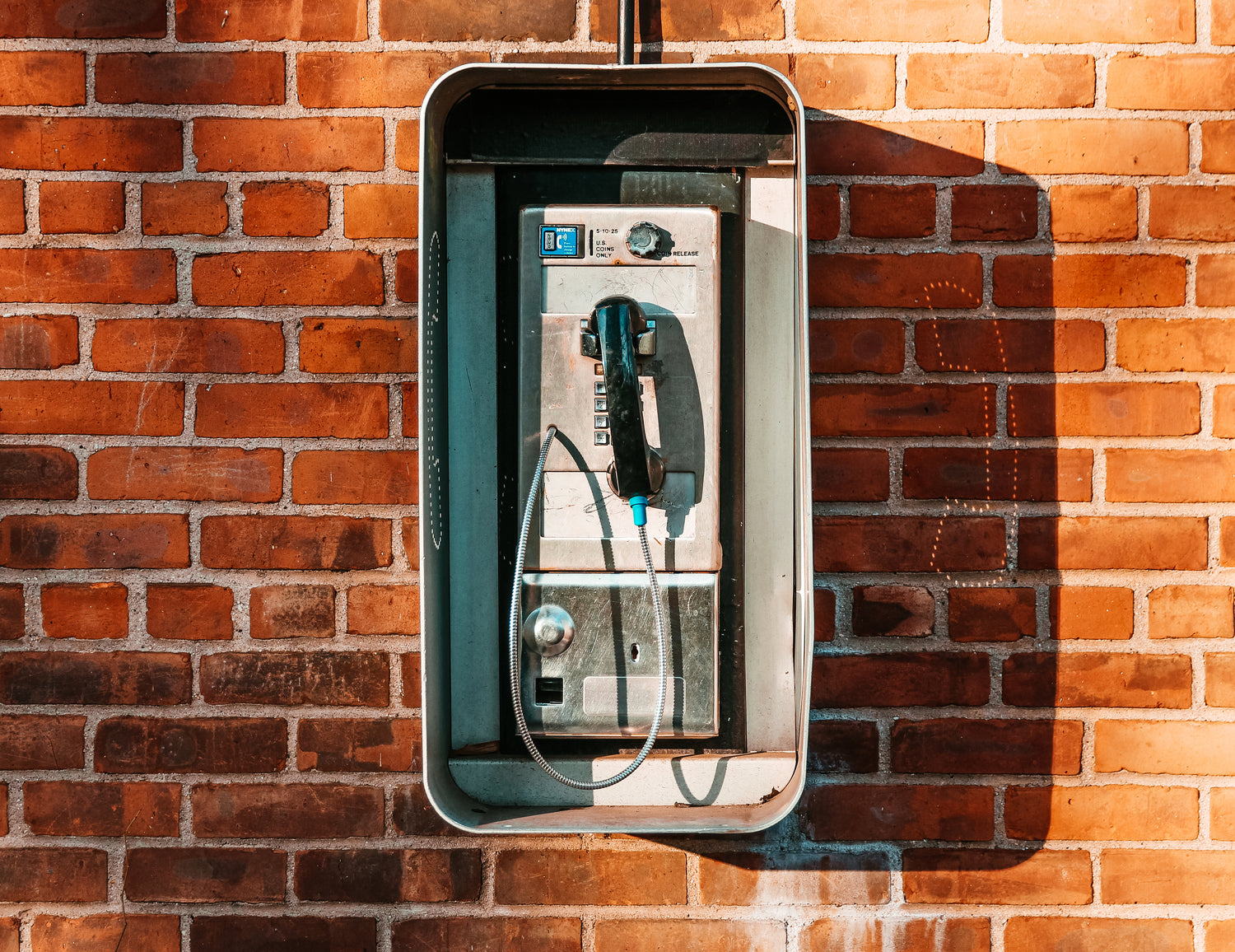 uralte amerikanische Telefonzelle vor einer Backsteinwand