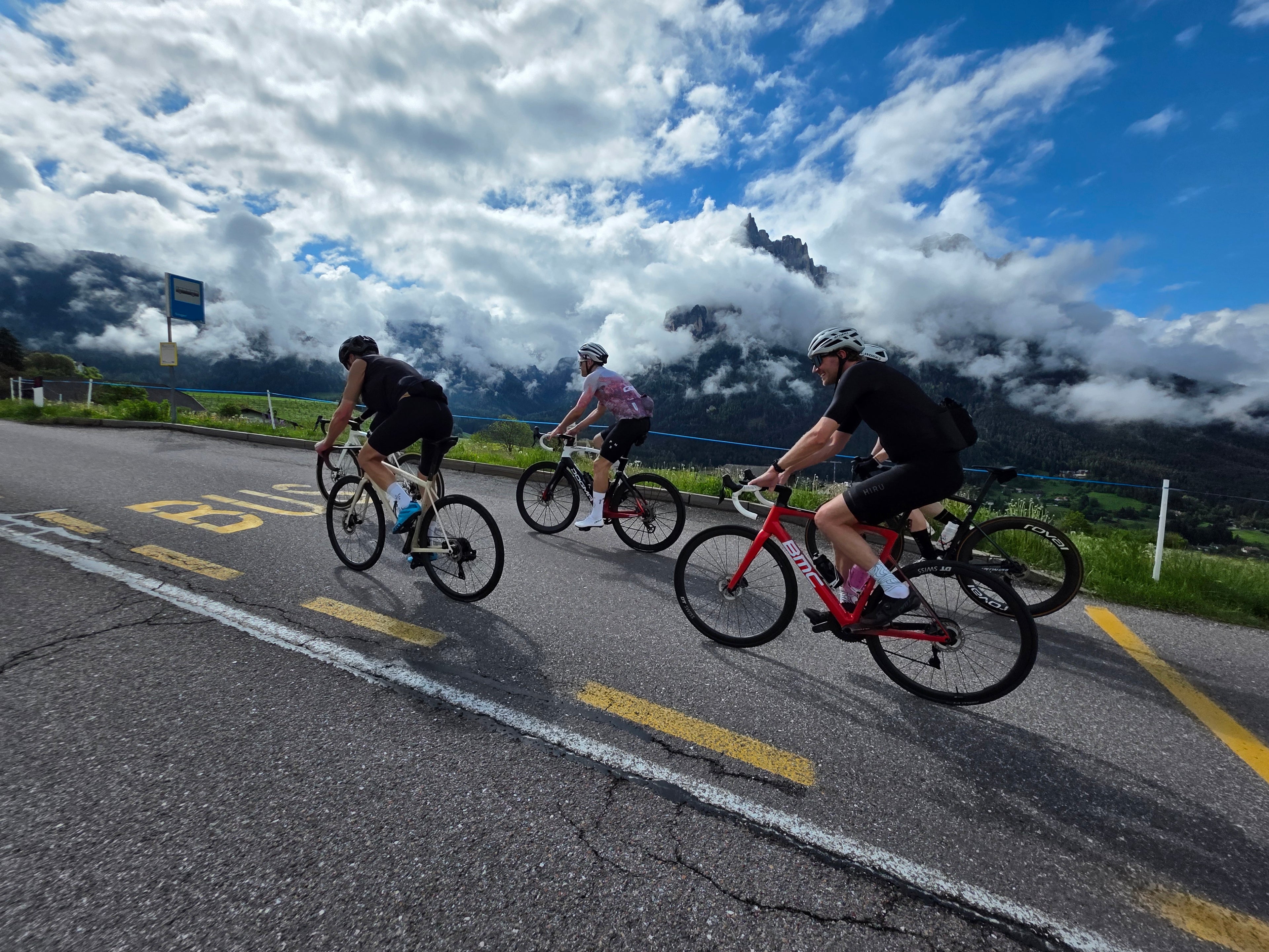 Rennradfahrer auf einer Alpenstraße vor wolkenverhangenen Bergen